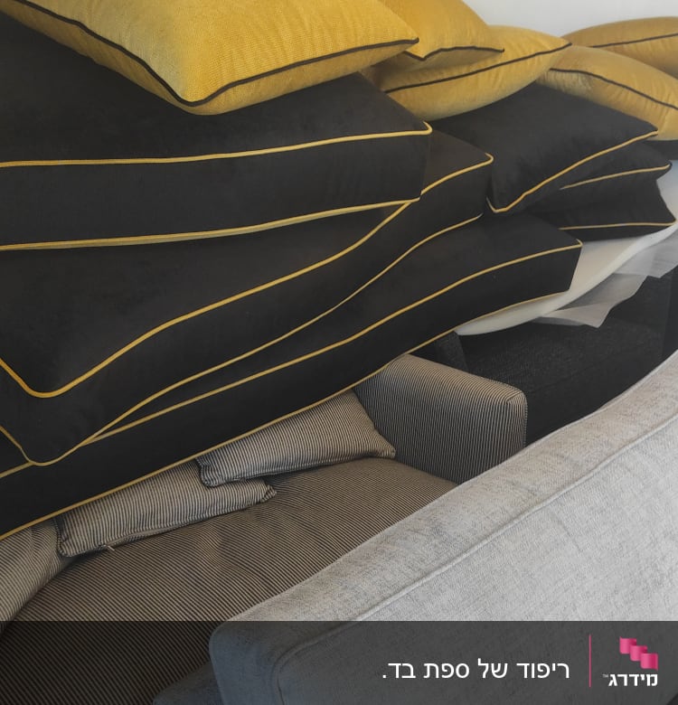 כריות גדולות בצבעים שחור וצהוב מונחות על ספה